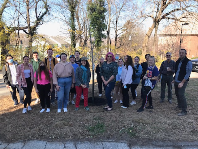 Students, faculty, and staff gathered around the newly planted tree