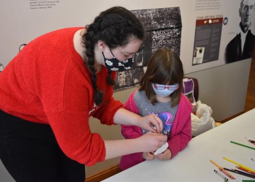 Abigail is shown here helping children color German(-American) pickles for their Christmas tree, a holiday craft she developed. 